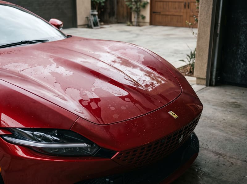 Ceramic coating in Los Angeles: the hood of a red Ferrari Roma with water spots and water sheeting on dull paint