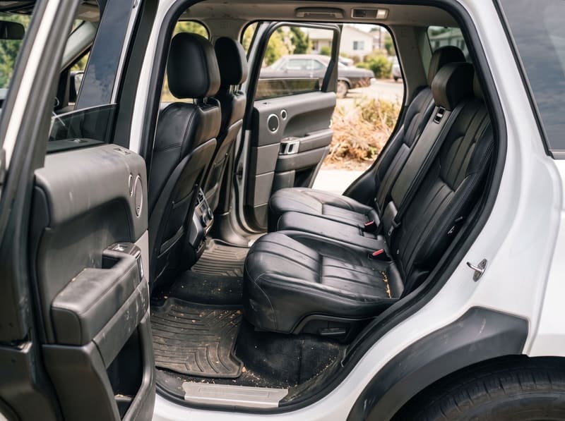 Car detailing near me in Los Angeles: the rear seats of a white Range Rover with crumbs, greasy patches on the black leather and dirty floor mats